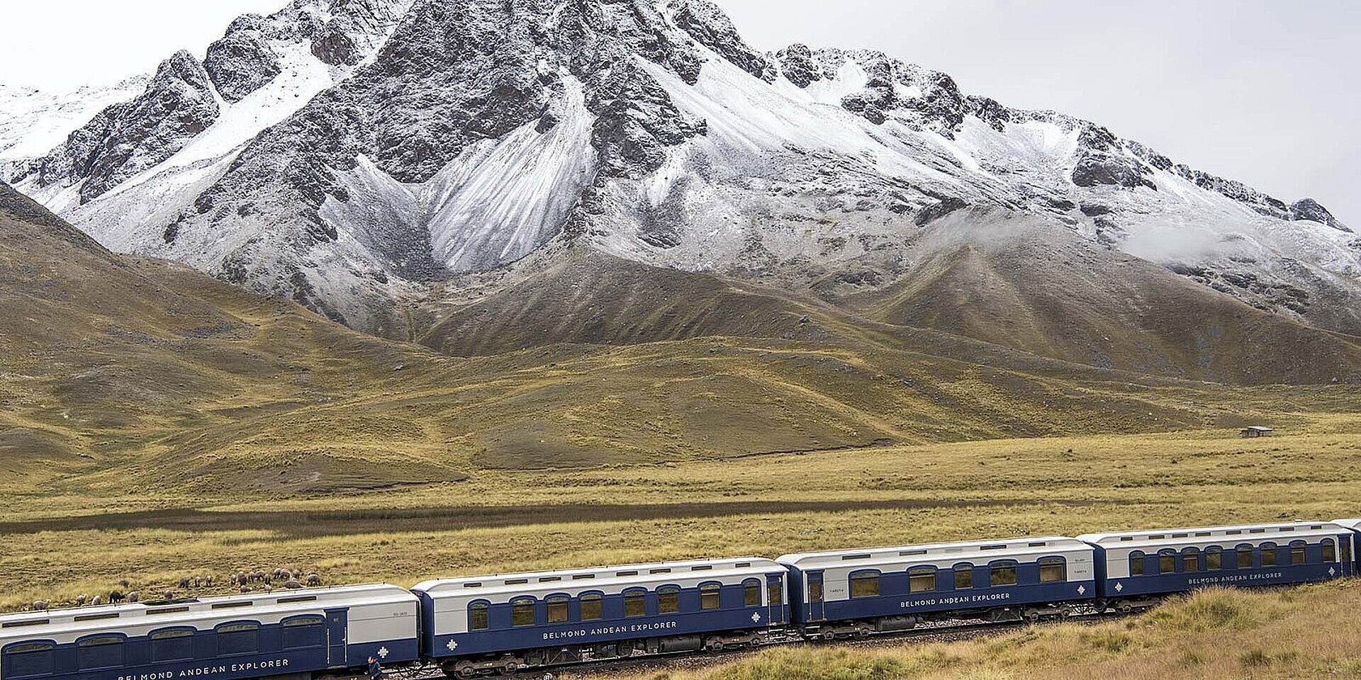 Der Zug Andean Explorer vor leicht beschneiten Bergen im peruanischen Hochland.