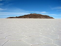 Weiße Salzwüste mit Bergen in der Ferne und blauem Himmel